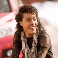 Smiling Woman Wearing Black Lace Top Outdoors Near a Red Car